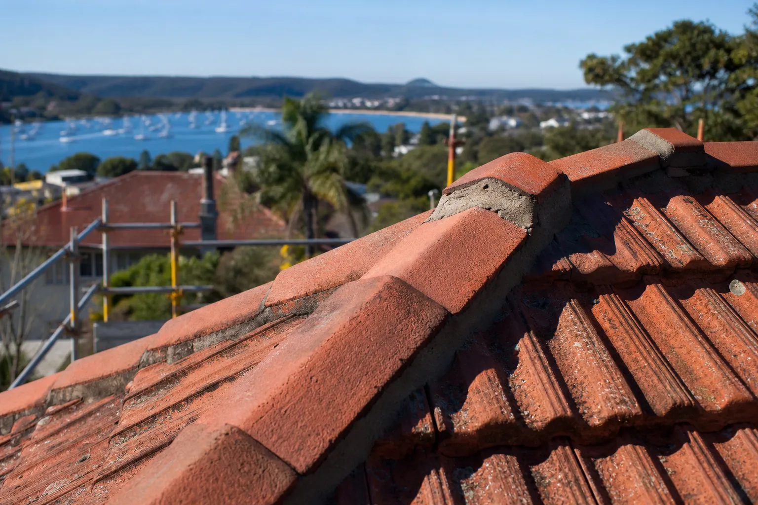 Roofer applying fresh flexible pointing to ridge caps on a Central Coast tile roof