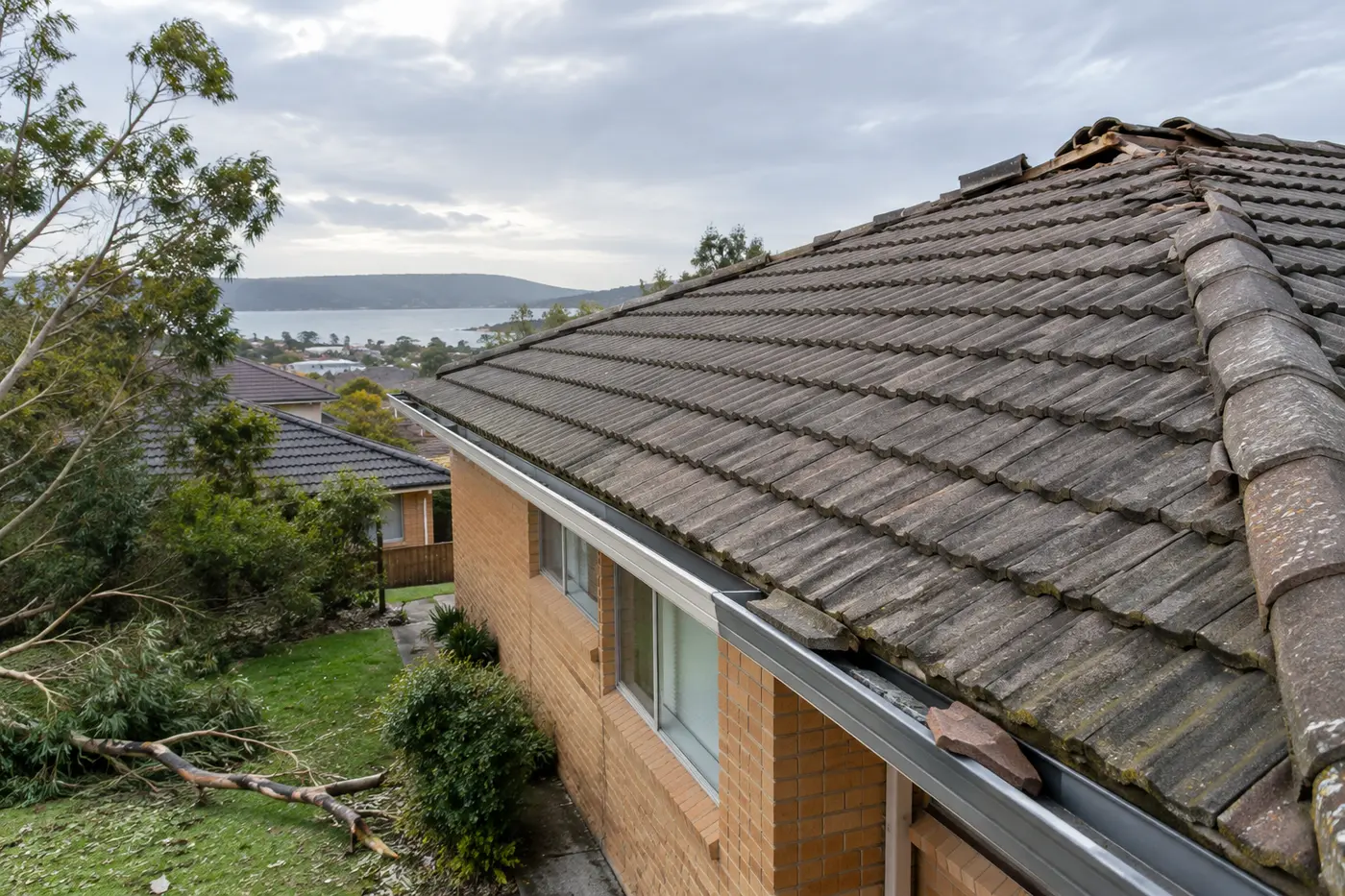 Tiled roof on a Central Coast home after a storm, with ridge capping missing and broken tiles in the gutter