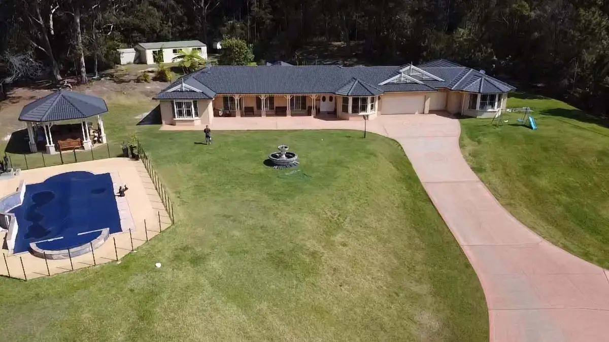 Aerial view of an acreage home with a restored charcoal tile roof, a pool and a long driveway