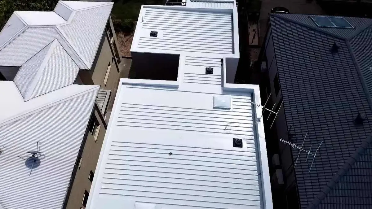 Aerial view of a long white flat pan metal roof on a new build