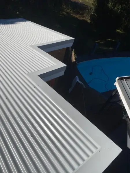 New pale metal roof stepping around a backyard pool
