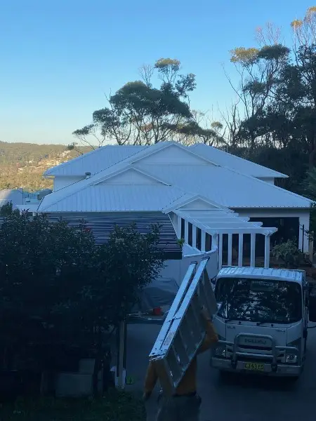 Hillside home with a new pale metal roof, the work truck parked in the driveway