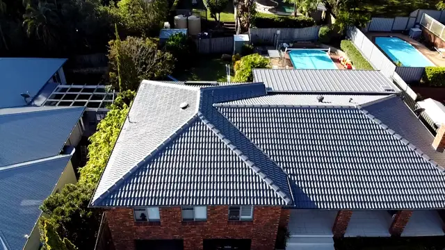 Two storey brick home in Wamberal with its tile roof restored and coated in Colorbond Basalt